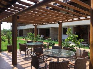 a patio with tables and chairs under a wooden pergola at Vilage beira mar in Itacimirim