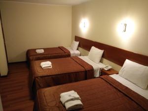 Habitación de hotel con 3 camas y toallas. en Hostal Qoyllurwasi, en Arequipa