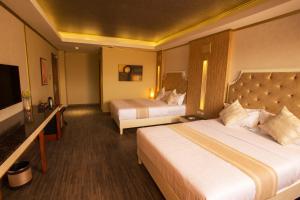 a hotel room with two beds and a television at Appleton Boutique Hotel Mactan Cebu in Mactan
