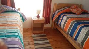 um quarto com 2 camas individuais e uma mesa de cabeceira em Cabañas Antomai em Pichilemu