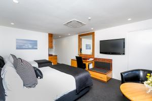 a bedroom with a bed and a tv and a table at Plymouth International in New Plymouth