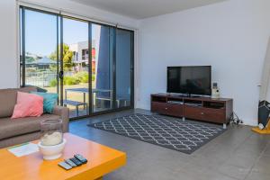 a living room with a couch and a tv at 3 Bedroom Townhouse - Poolside - Free Parking in Torquay