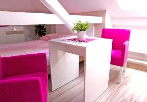 a room with a table and pink chairs and a bed at Willa Przy Plaży in Pogorzelica