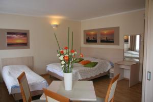 a room with a bed and a table with flowers on it at Willa Przy Plaży in Pogorzelica