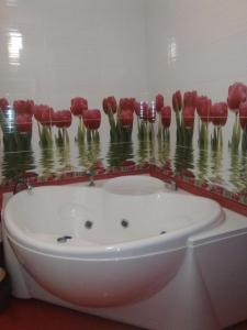 a bath tub with red flowers on a wall at Apartments Galactika in Oral