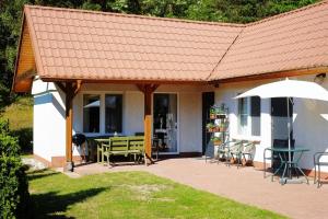 a house with a roof with a table and an umbrella at Domek Letniskowy Pod Lasem in Gdańsk