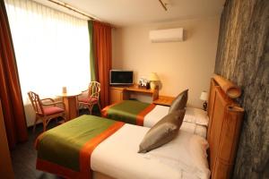 Habitación de hotel con 2 camas y escritorio en Hotel La Roseraie, en Wemmel