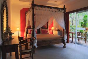 a bedroom with a canopy bed and a desk at Aquarius Beach Hotel in Sanur