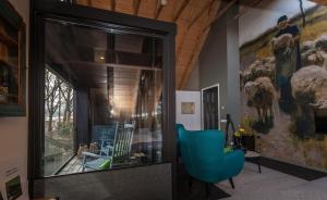 een woonkamer met een blauwe stoel en een groot raam bij Bed & breakfast Hoeve Springendal in Hezingen