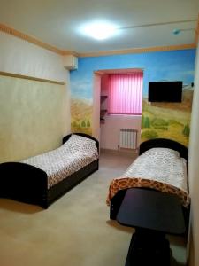 エッセントゥキにあるГостевой дом Ессентукиのベッドルーム1室(ベッド2台付)が備わります。壁には絵画が飾られています。