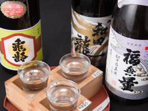 dos botellas de vino y dos vasos en una bandeja de madera en Masuya Ryokan, en Aoki