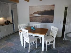 a kitchen with a wooden table and white chairs at Witzuk, ruhiges Strandhaus in Warnkenhagen