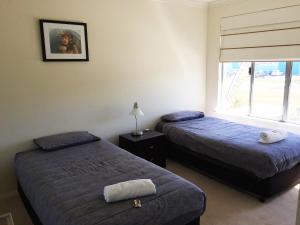 two beds in a room with a window at Blue Sky Apartment in Jurien Bay