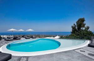 uma piscina com cadeiras e guarda-sóis em Anchor Suites em Oia