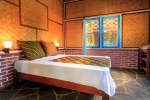 a bed in a room with a brick wall at Woodstock In The Village in Singaraja