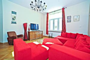 a living room with a red couch and a tv at Red Apartment Czyżewskiego by Grand Apartments in Sopot