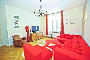 ein Wohnzimmer mit einem roten Sofa und einem TV in der Unterkunft Red Apartment Czyżewskiego by Grand Apartments in Sopot