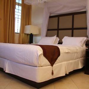 1 dormitorio con 1 cama blanca grande con dosel en ShaMooL Hotel, en Dar es Salaam