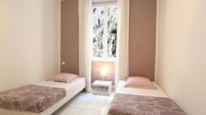 two beds in a room with a window at Résidence Rauba Capeu in Nice