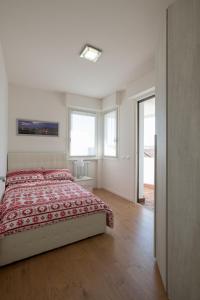 a white bedroom with a bed and two windows at Nuovissimo e luminoso appartamento centro Pordenone in Pordenone