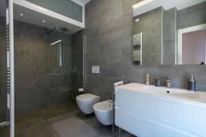 a bathroom with a sink and a toilet and a mirror at Nuovissimo e luminoso appartamento centro Pordenone in Pordenone