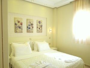 a bedroom with a white bed with three pictures on the wall at Hotel Aeollos in Pefkochori