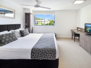 een slaapkamer met een bed, een bureau en een raam bij Fairshore Noosa in Noosa Heads