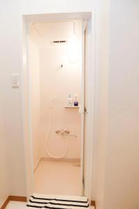 a shower in a white bathroom with a sink at Guest House En in Nara