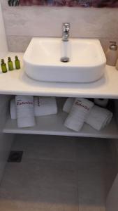 a bathroom with a sink and towels on a shelf at Katerina Apartments & Studios in Naousa