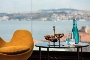 einen Tisch mit einer Flasche, zwei Gläsern und einem Stuhl in der Unterkunft Metropolitan Hotels Bosphorus - Special Category in Istanbul