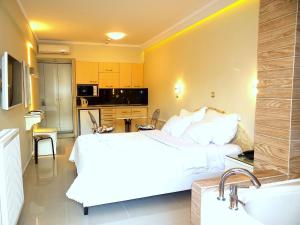 a bedroom with a large white bed and a kitchen at Hotel Aeollos in Pefkochori