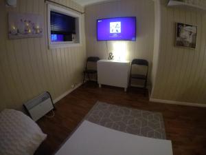 ein Zimmer mit einem Fernseher an der Wand und zwei Stühlen in der Unterkunft Apartment near the airport in Tromsø + 8 Fotos
