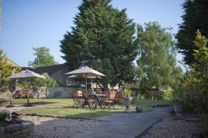 eine Terrasse mit Tischen und Sonnenschirmen im Hof in der Unterkunft The White Hart in Somerton