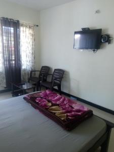 a room with a bed and chairs and a tv at Dream Nest Resorts in Kotagiri