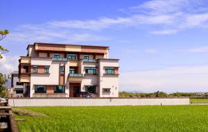 a building with a green field in front of it at Home of 120 B&B in Jiaoxi