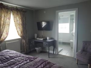 a bedroom with a bed and a desk with a television at The Angel Inn in Warminster