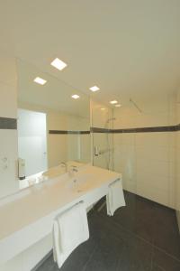 La salle de bains est pourvue d'un lavabo et d'un grand miroir. dans l'établissement qubixx stadtmittehotel, à Schwäbisch Hall