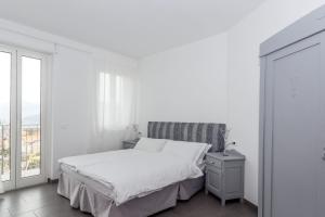 a white bedroom with a bed and a window at Minerva Residence in Lavena Ponte Tresa