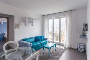 un soggiorno con divano blu e tavolo in vetro di Minerva Residence a Lavena Ponte Tresa