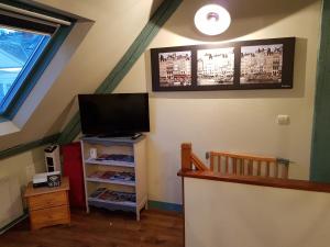 a attic room with a tv and a staircase at La Petite Parenthèse in Honfleur