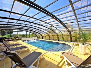 a conservatory with a pool with chairs and a table at Les Ventoulines in Domme