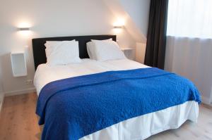 a bedroom with a large bed with a blue blanket at B&B Aquavit in Knokke-Heist
