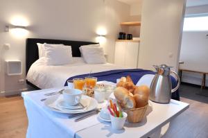 Zimmer mit einem Bett und einem Tisch mit Brot und Getränken in der Unterkunft B&B Aquavit in Knokke-Heist