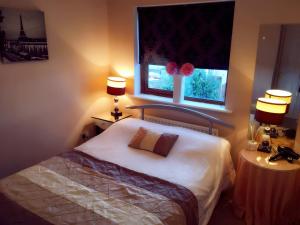 a bedroom with a bed and a window with two lamps at Summer Cottage in Kinsale in Kinsale