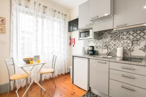 a kitchen with white cabinets and a table with chairs at A Francos Burguer Station 2 in Porto +8 photos