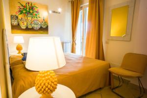 una lámpara sentada en una mesa junto a una cama en La Residenza Dei Mori - Taormina Holidays en Taormina