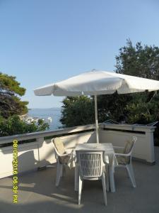 a white table and chairs under an umbrella at Sea View Room Macolic in Rab