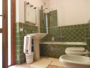 Baño de azulejos verdes con lavabo y aseo en Appartamenti Galatea en Palau