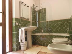 a green tiled bathroom with a sink and a toilet at Appartamenti Galatea in Palau