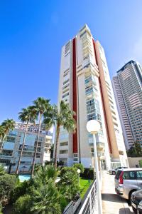 a tall building with palm trees in front of it at Residence Vacanza Torre Montecarlo in Benidorm